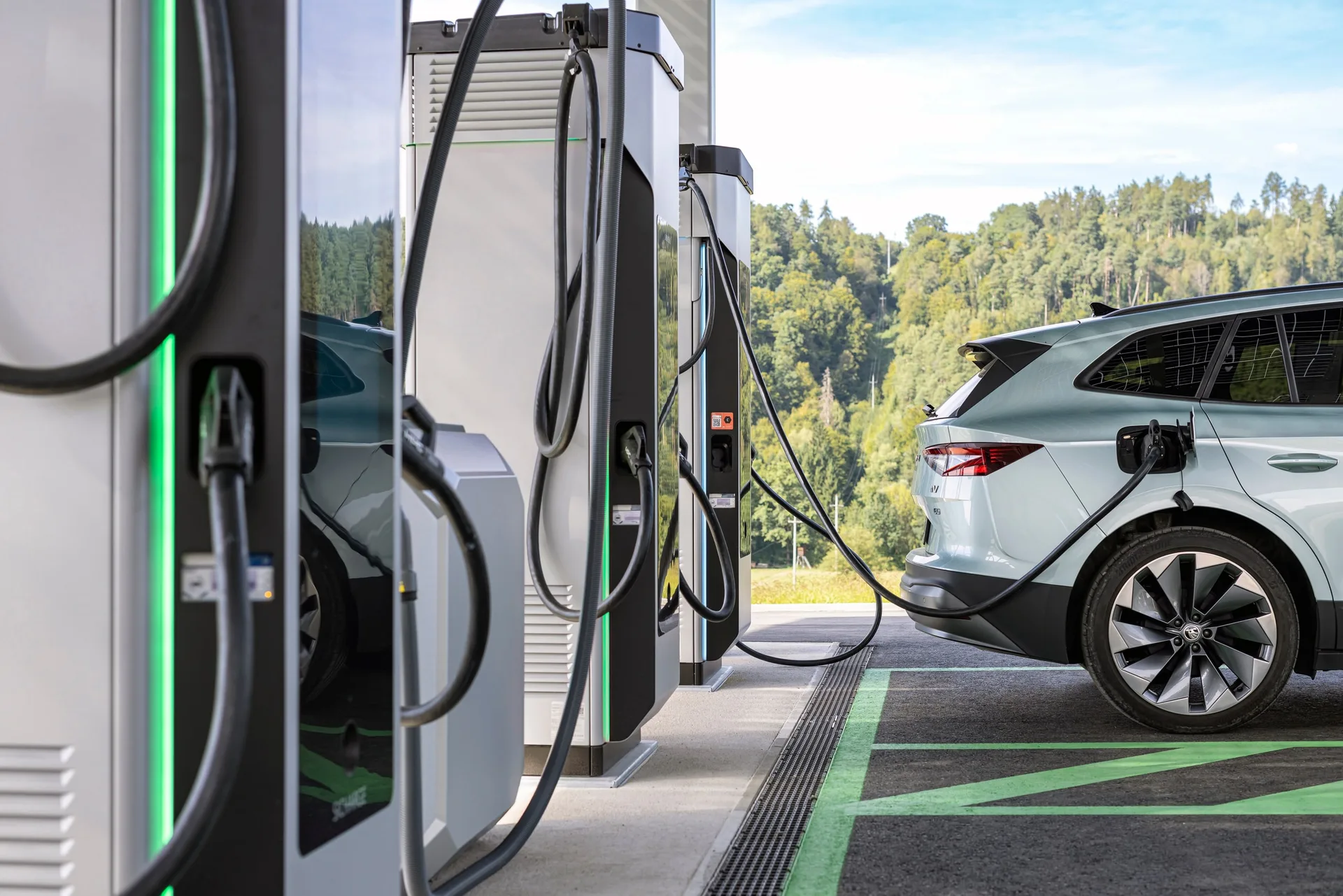 Säule mit grüner Lichtkante, das Ladekabel steckt im Auto