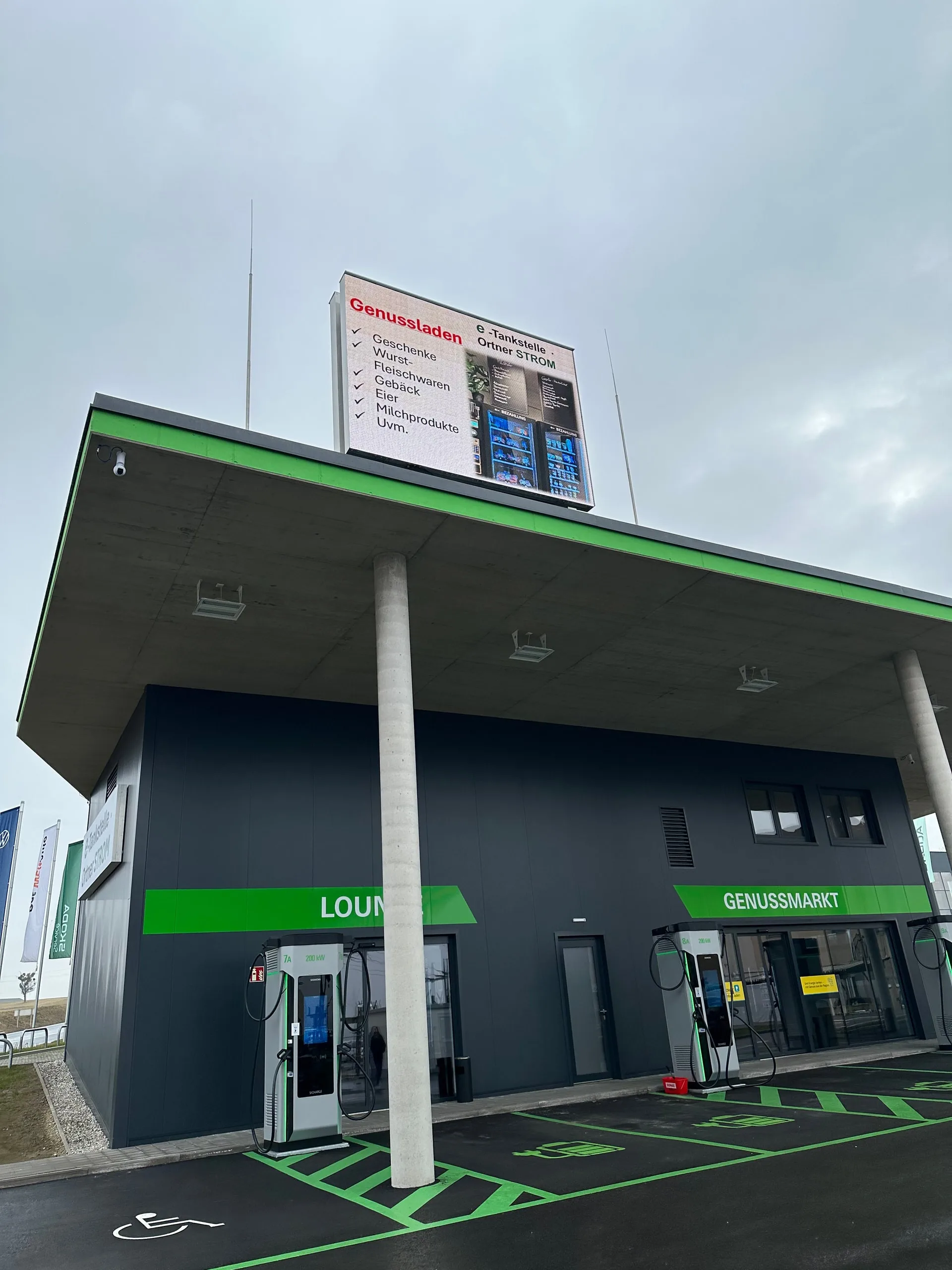 Gebäude von vorne, Leuchtanzeige wirbt für den Genussladen