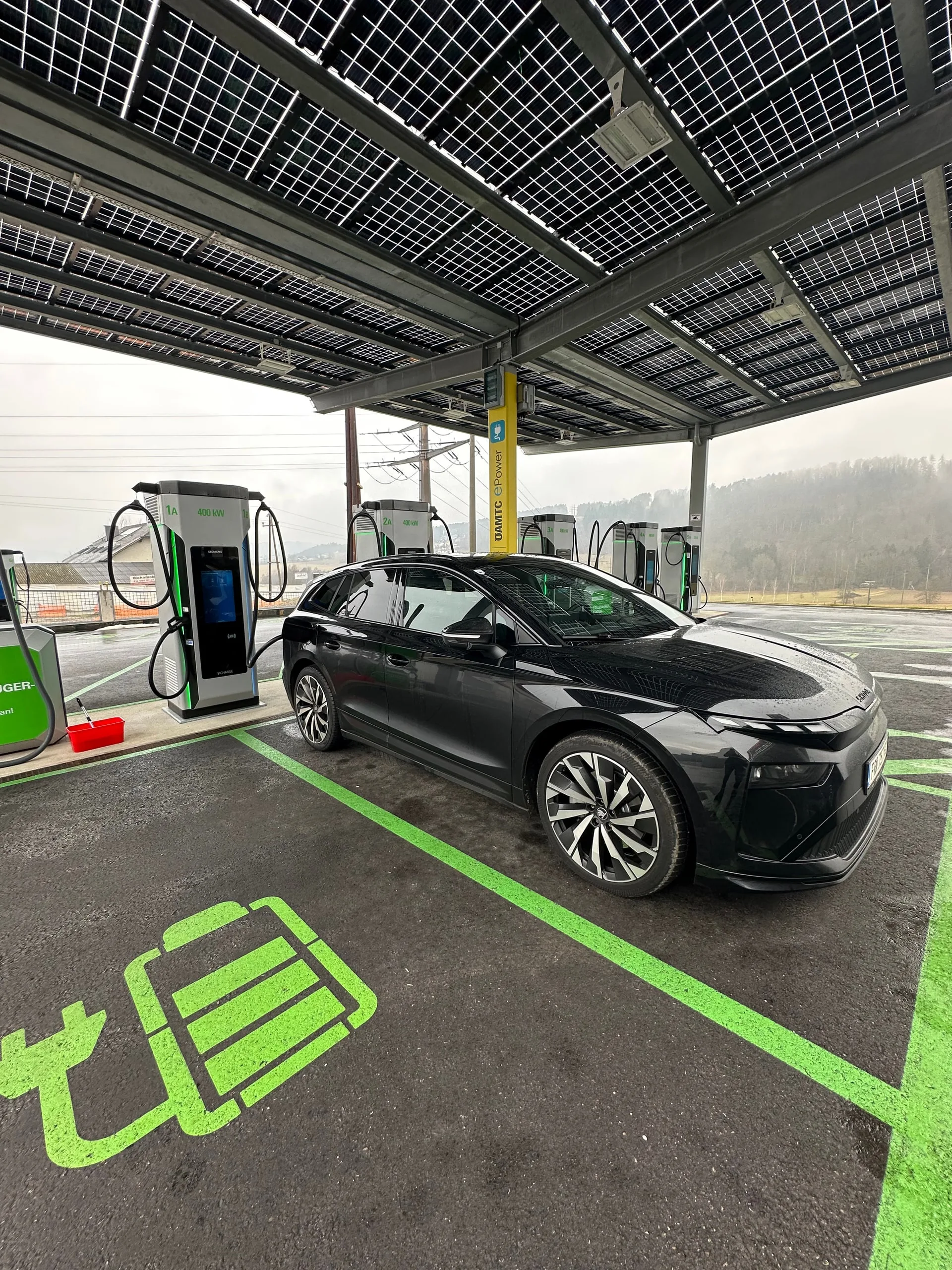 Elektroauto auf einem grün markierten Ladeplatz unter dem Vordach