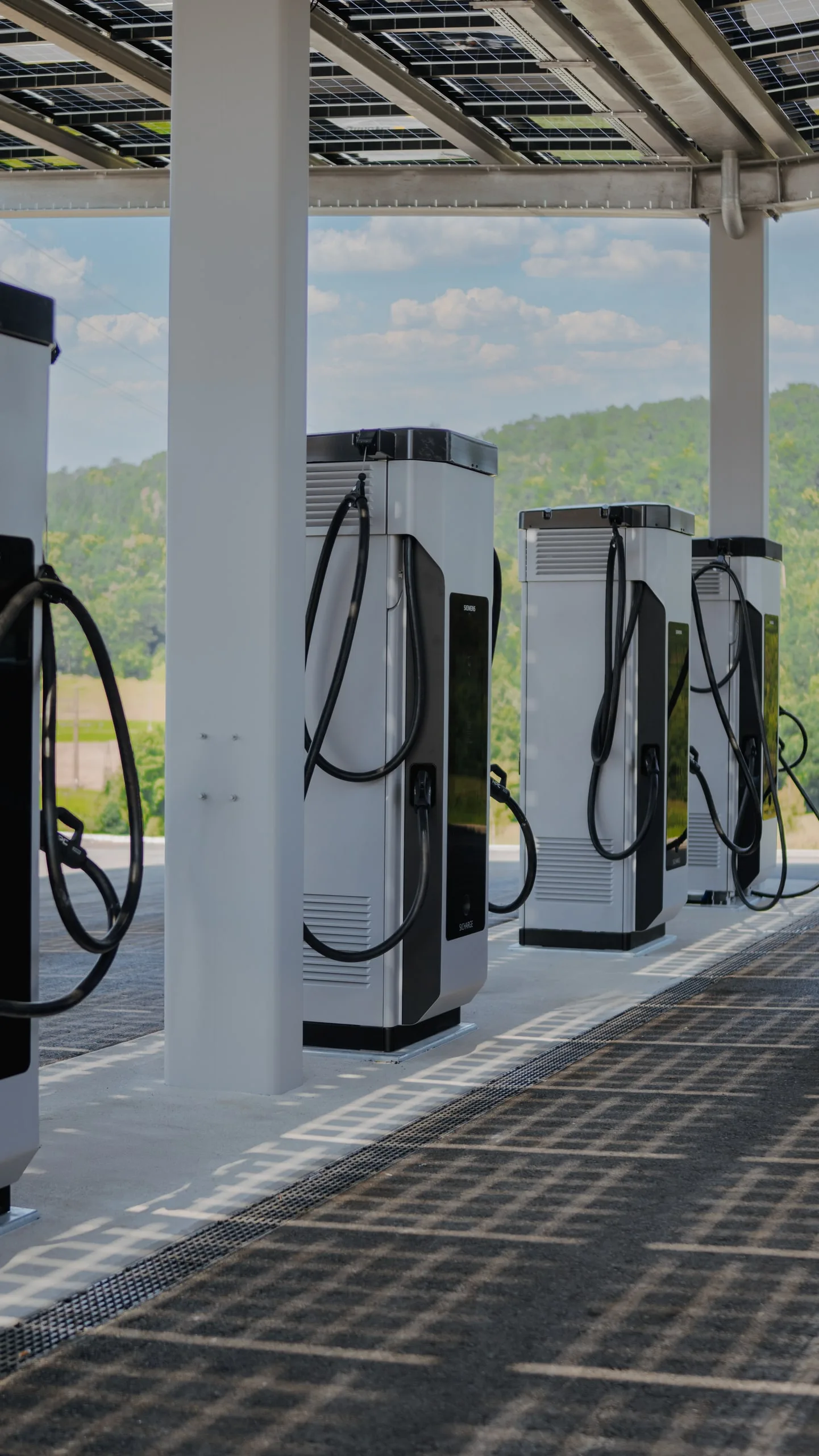 Säulenreihe unter dem Photovoltaik-Vordach, dahinter bewaldete Hügel