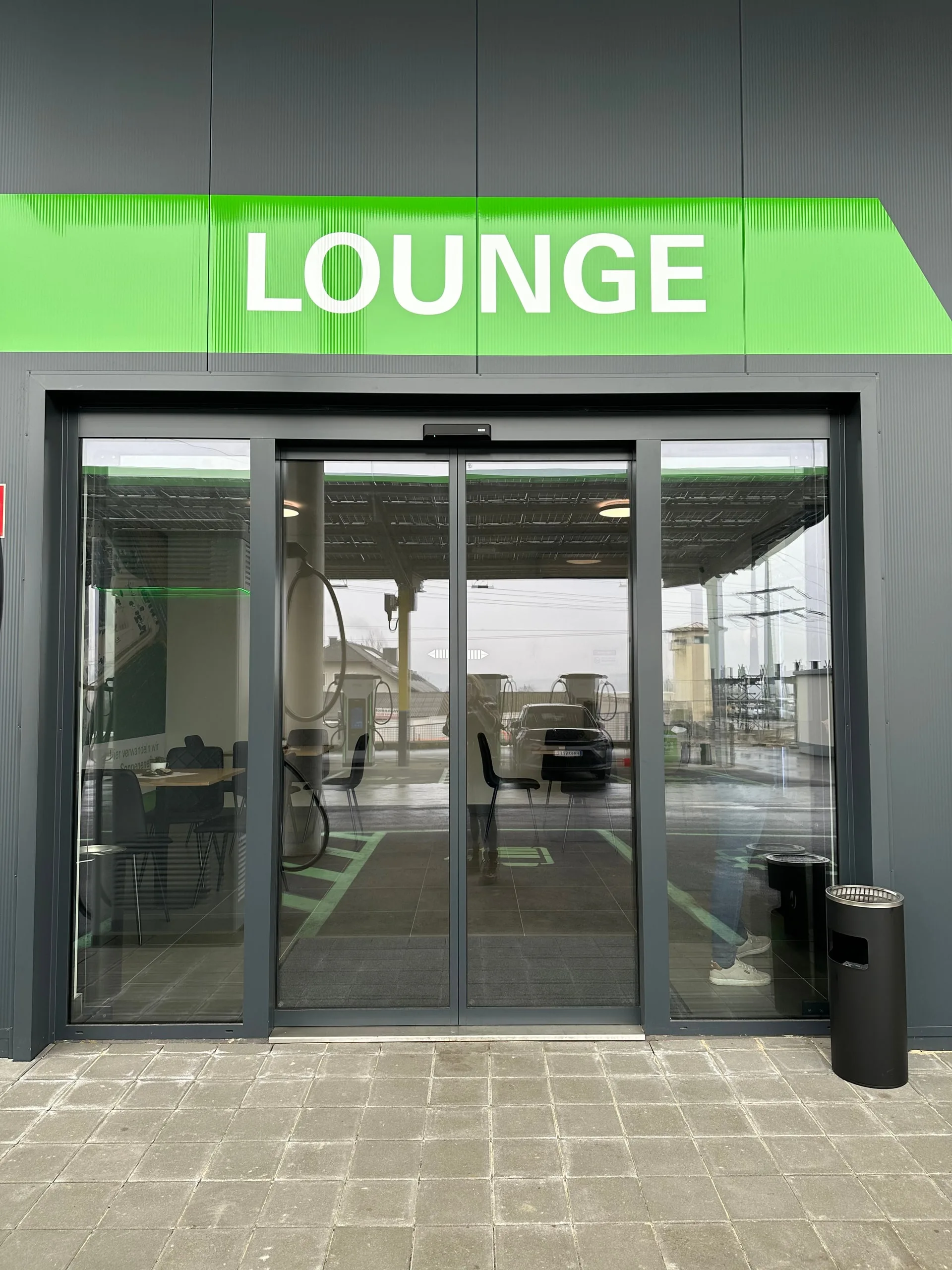 Glastür zur Lounge mit grünem Schriftzug über dem Eingang